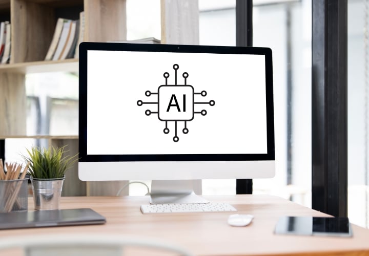 Modern computer monitor on a wood desk in an office setting with a graphic representing AI on the screen.