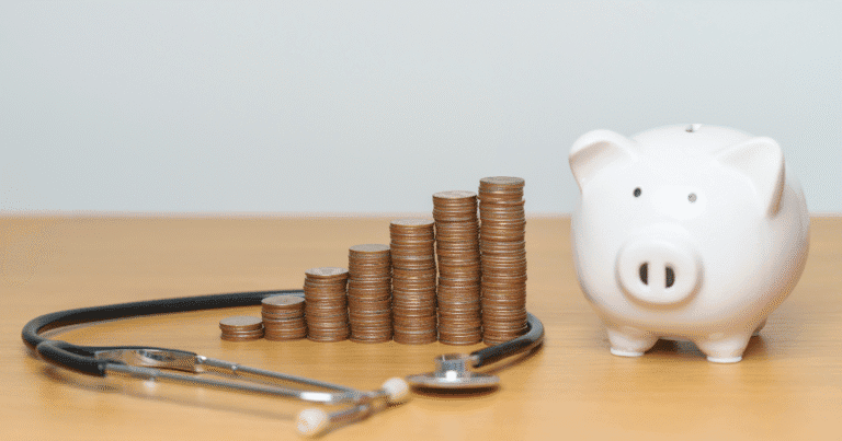 Photo of a piggy bank, pile of money, and a stethoscope.