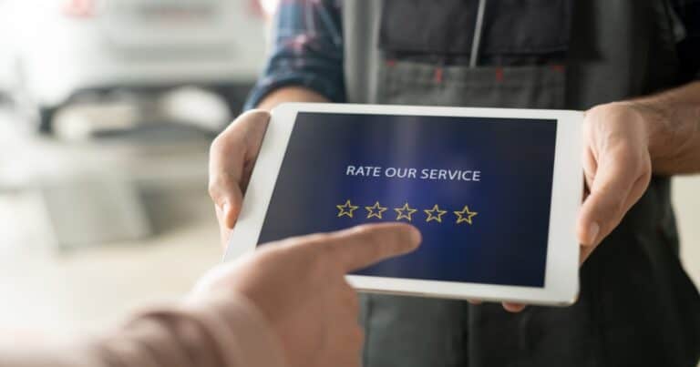 A technician is holding a tablet with five stars on its screen while a customer is going to rate the service.